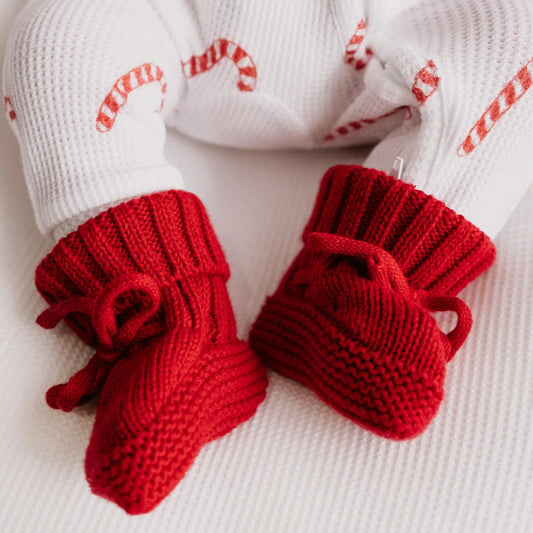 Red knitted baby booties on a white background